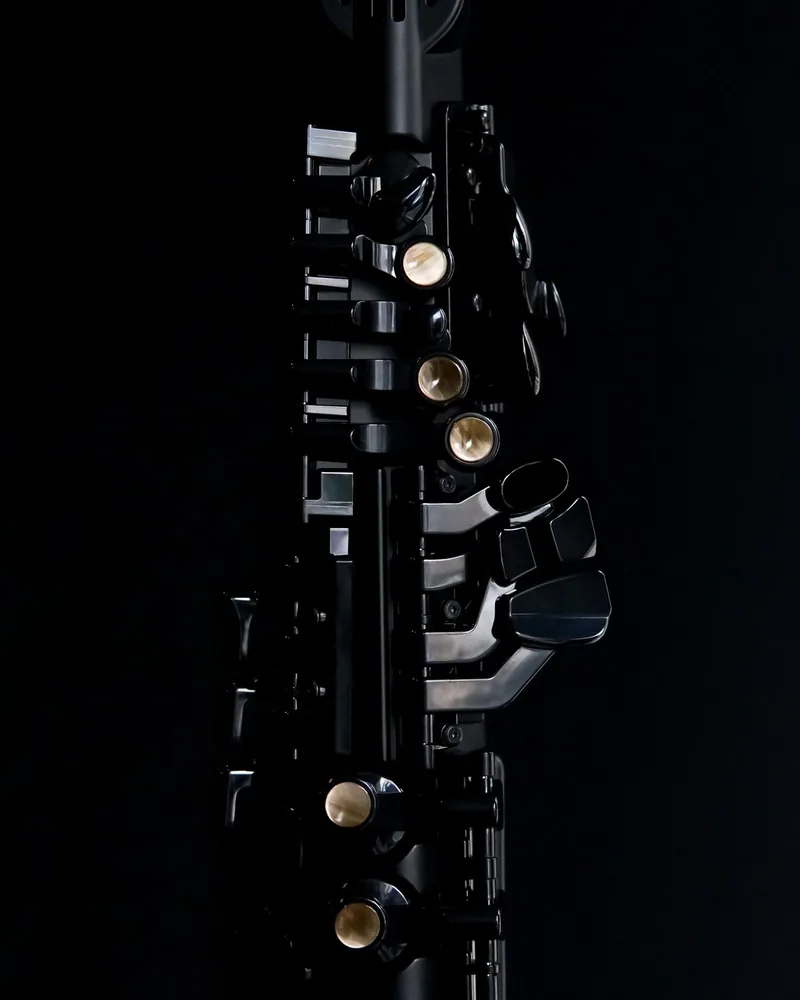 Detalle de las llaves y anillos de un clarinete sobre fondo oscuro